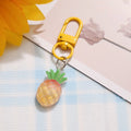One golden-yellow pineapple charm with green crown and yellow clasp from the matching pair