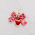 Red-and-white gingham bow with a strawberry pendant and gold-tone clip