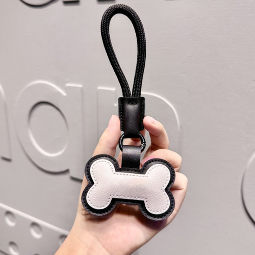 Cream bone loop bag charm with black border and hanging loop; supplier product photo