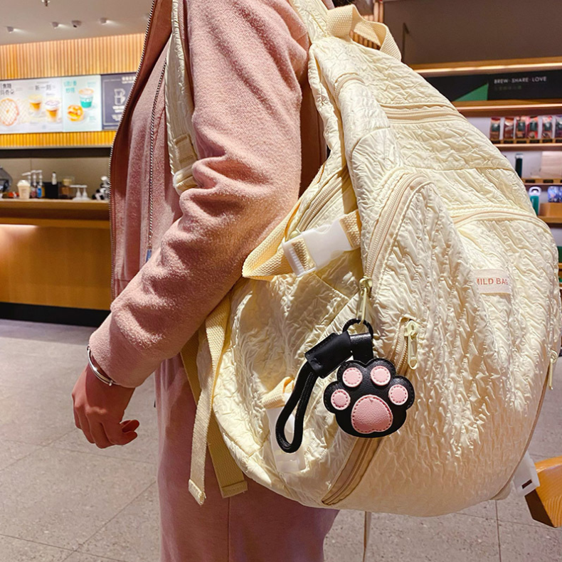 Pink paw loop bag charm attached to a cream backpack; bag not included