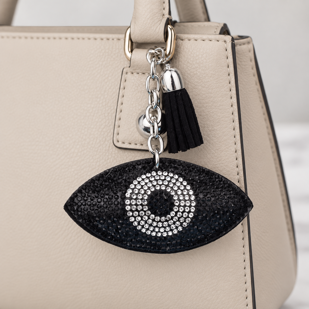 Evil Eye Crystal Bag Charm attached to a neutral handbag — AI context hero