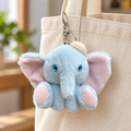 Blue elephant plush charm with glossy eyes attached to a cream tote