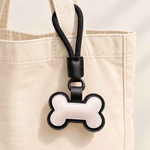 Cream bone loop bag charm styled on a beige canvas bag; bag not included