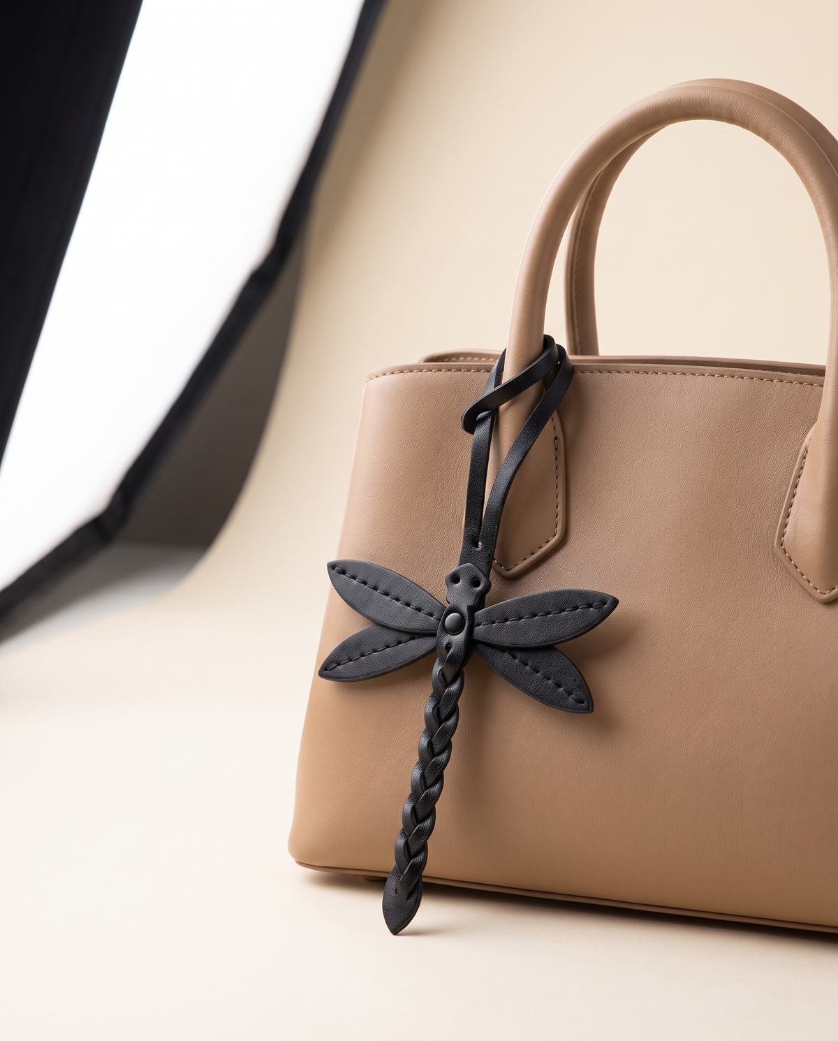 Dragonfly tassel bag charm attached to a warm beige handbag