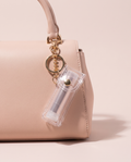 Transparent lip balm holder charm on a blush handbag