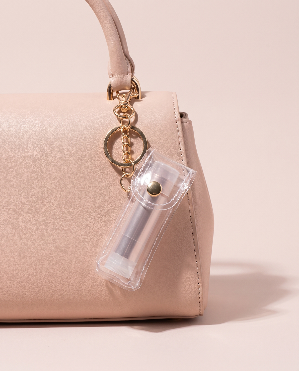 Transparent lip balm holder charm on a blush handbag