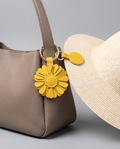 Magnetic hat and scarf clip holding a lightweight cream hat on a taupe handbag