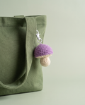 Purple and cream crochet mushroom charm on a moss green tote