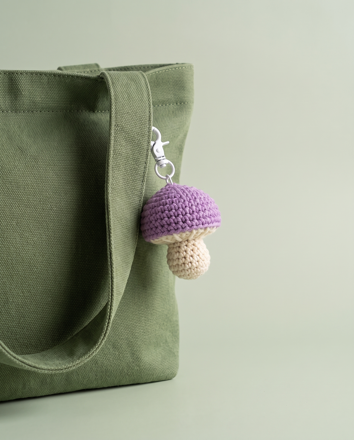 Purple and cream crochet mushroom charm on a moss green tote