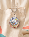 City mini mirror pocket case charm attached to a cream canvas tote