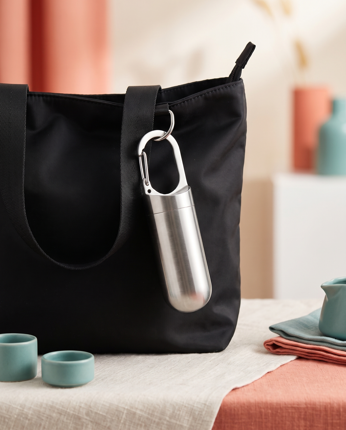 Stainless sealed capsule keychain on a black nylon tote