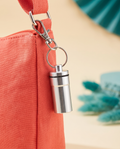 Mini outdoor aluminum capsule charm on a coral crossbody bag