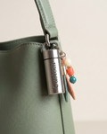 Waterproof stainless mini case charm on a sage handbag