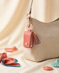 Leather hand sanitizer holder charm clipped to a neutral handbag