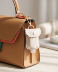PU leather sanitizer bottle sleeve charm on a tan handbag
