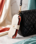 Leather sunglasses case pendant clipped to a black shoulder bag