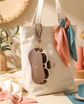 Soft leather glasses bag charm hanging from a cream canvas tote