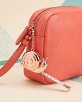 Mini snail tape measure charm on a coral crossbody bag