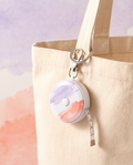 Retractable tape measure keychain charm clipped to a cream canvas tote