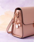 Mini rose-gold book flower rainbow charm clipped to a blush handbag
