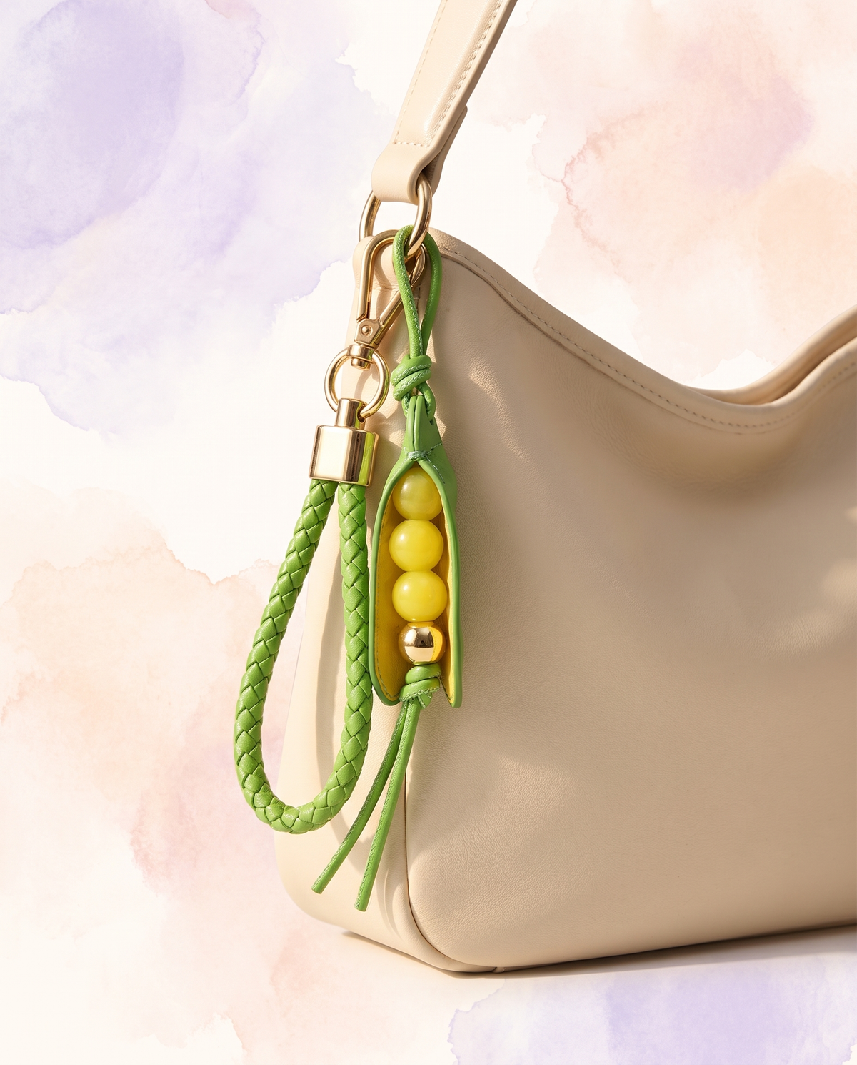 Leather pea pod bag charm clipped to a cream shoulder bag