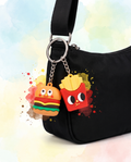 Mini burger and fries food charm clipped to a black crossbody bag