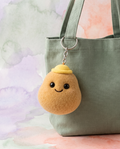 Plush smiling vegetable charm clipped to a sage canvas tote