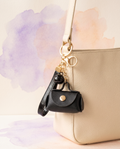 Tassel leather keyring pouch charm clipped to a cream shoulder bag