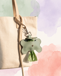 PU leather dog waste bag holder charm clipped to a neutral leash beside a cream tote