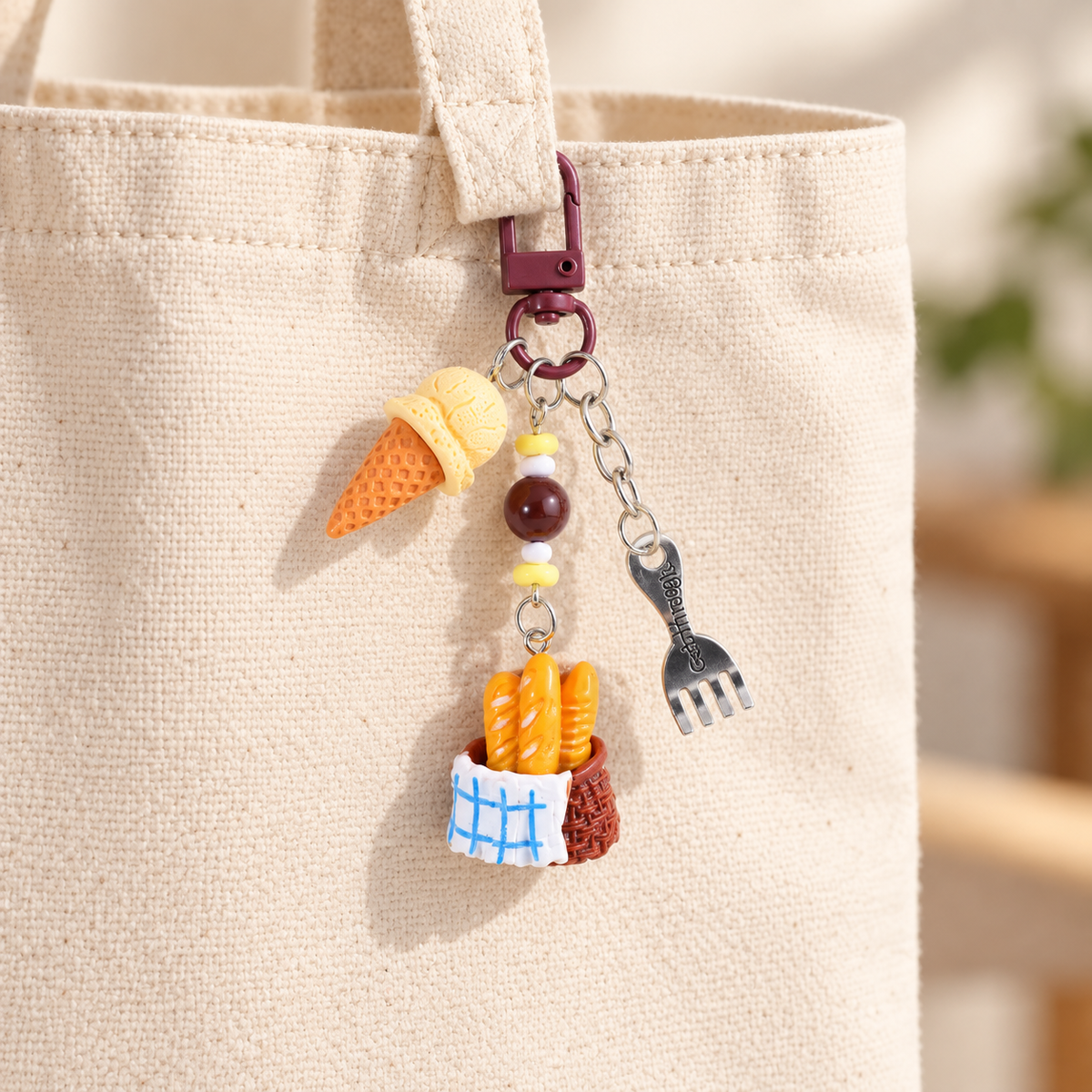 Vanilla ice cream and baguette basket charm clipped to a cream canvas bag; bag not included
