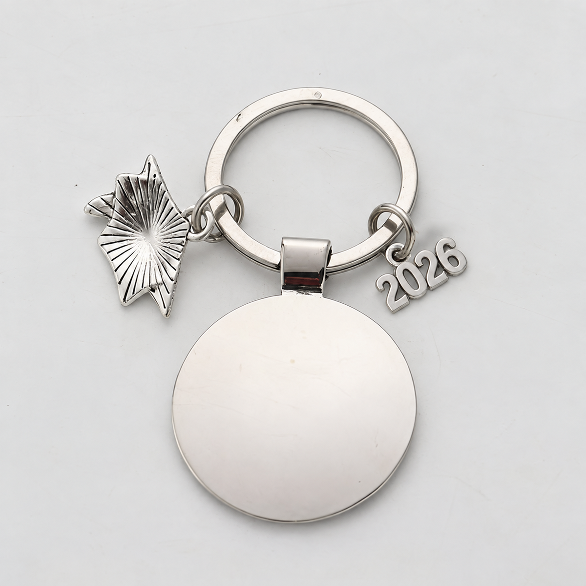 Silver-tone graduation charm reverse showing plain round back, keyring and reverse of cap