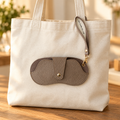 Brown bag charm attached to a canvas bag; bag not included