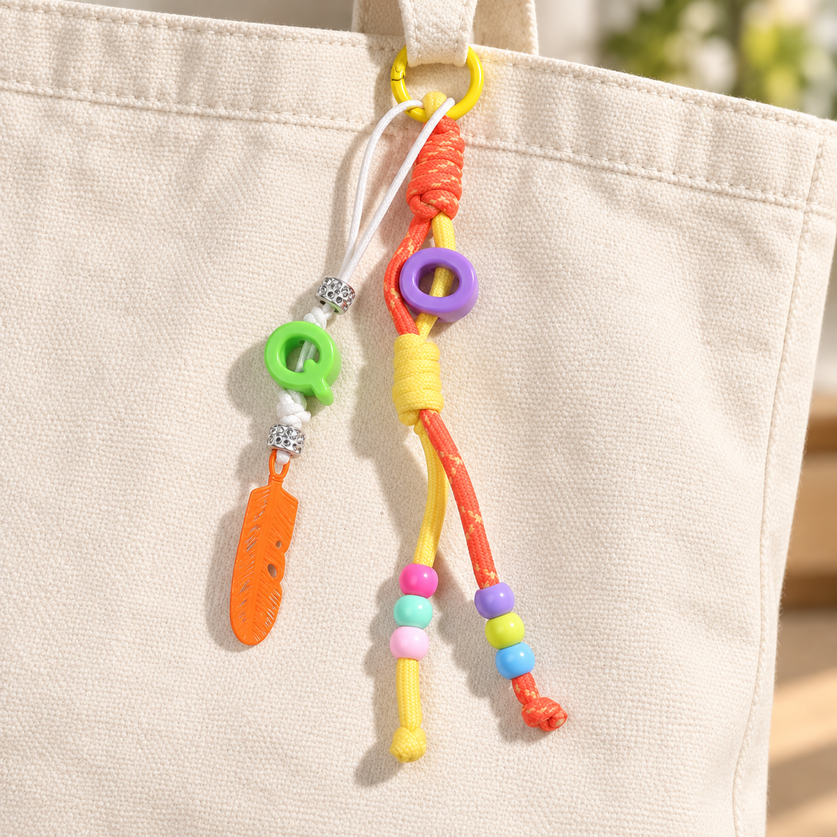 Yellow & orange bag charm attached to a canvas bag; bag not included