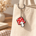 Red mushroom bag charm attached to a cream canvas tote; bag not included