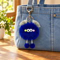 Cobalt blue pom-pom character with eyes, silver trim and feet attached to a denim bag; bag not included
