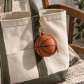 Sports-ball silicone mini pouch bag charm attached to a canvas tote